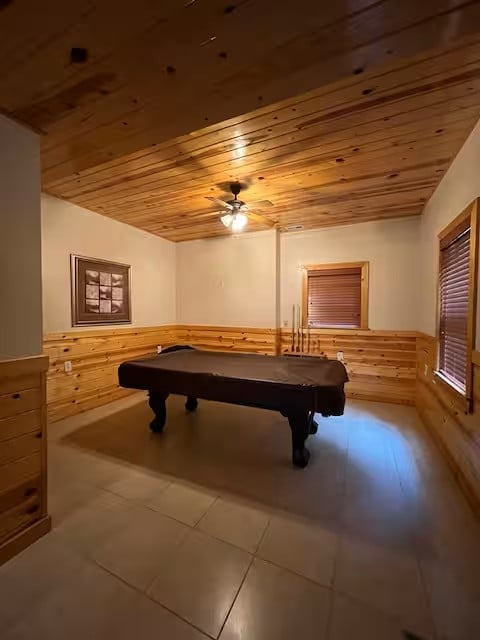 Empty recreation room with black pool table, wood ceiling and wainscoting, tile flooring, and window blinds