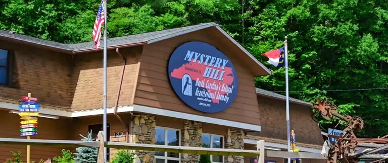 Brick building with Mystery Hill sign and American flag surrounded by green trees